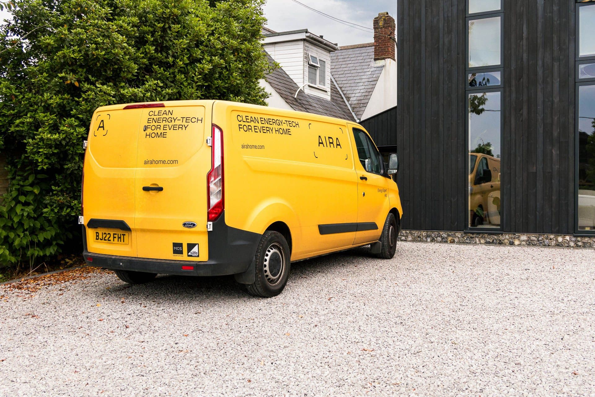 An Aira van parked on a gravel driveway in front of a customer's house