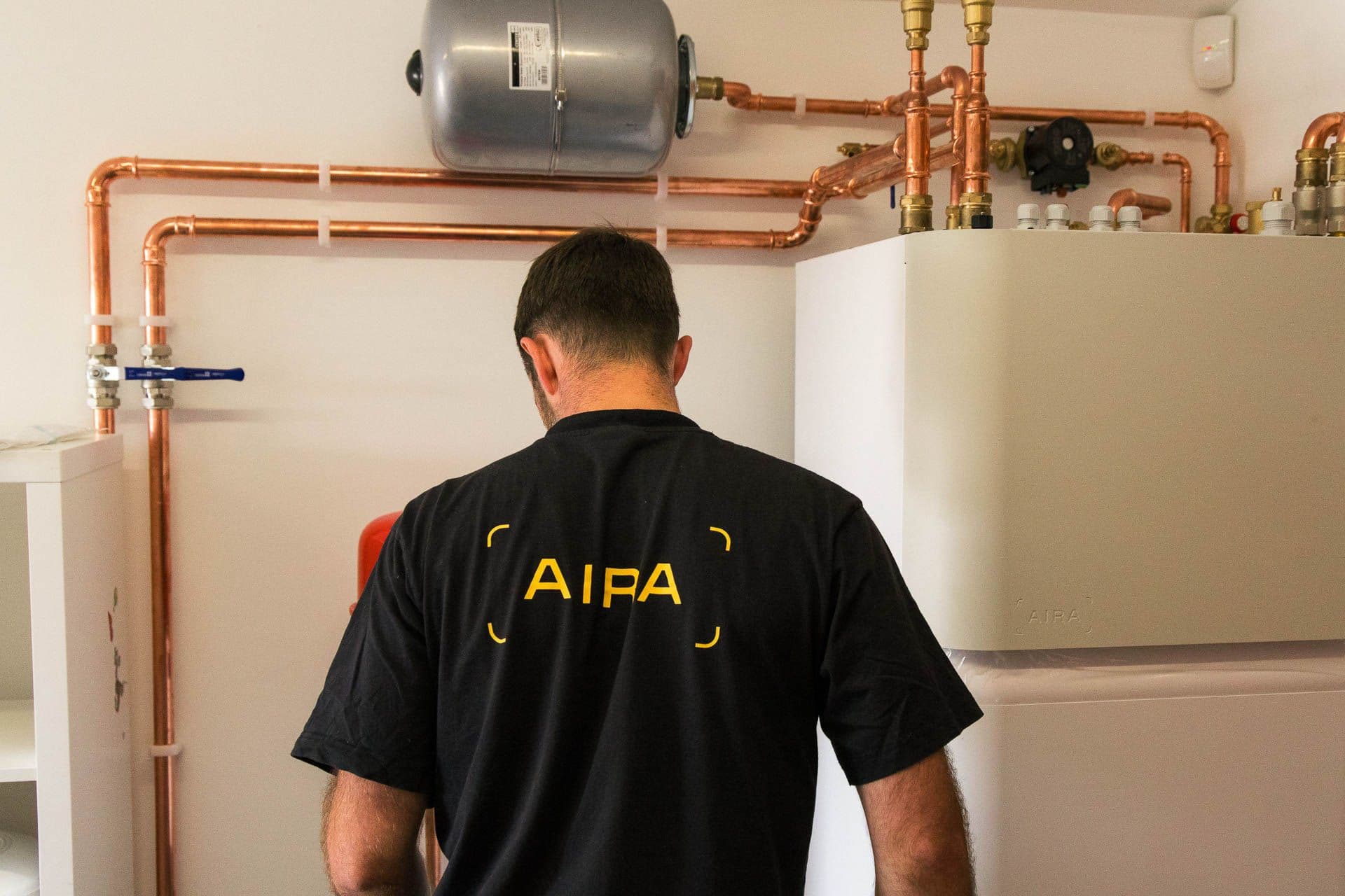 An Aira technician installing an Aira all-in-one heat pump indoor unit with the copper pipework running along the wall