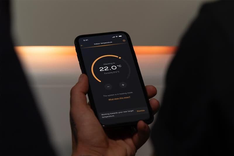 Woman holding up phone showing Aira Home Energy app for Aira Heat Pump