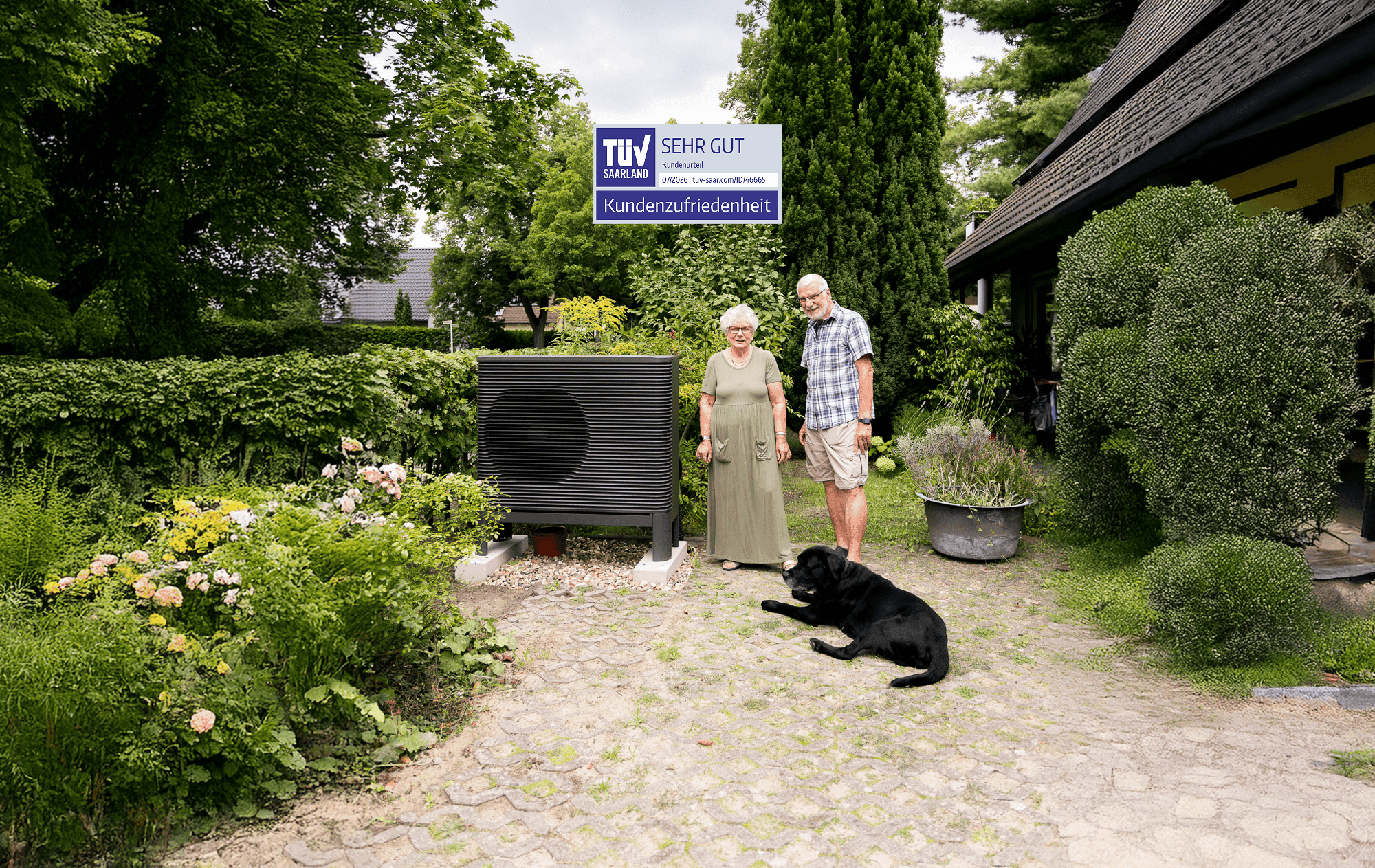 Ein Mann und eine Frau stehen mit ihrem Hund neben einer Aira Wärmepumpe. Über der Wärmepumpe ist das TÜV-Saarland-Siegel zu sehen.