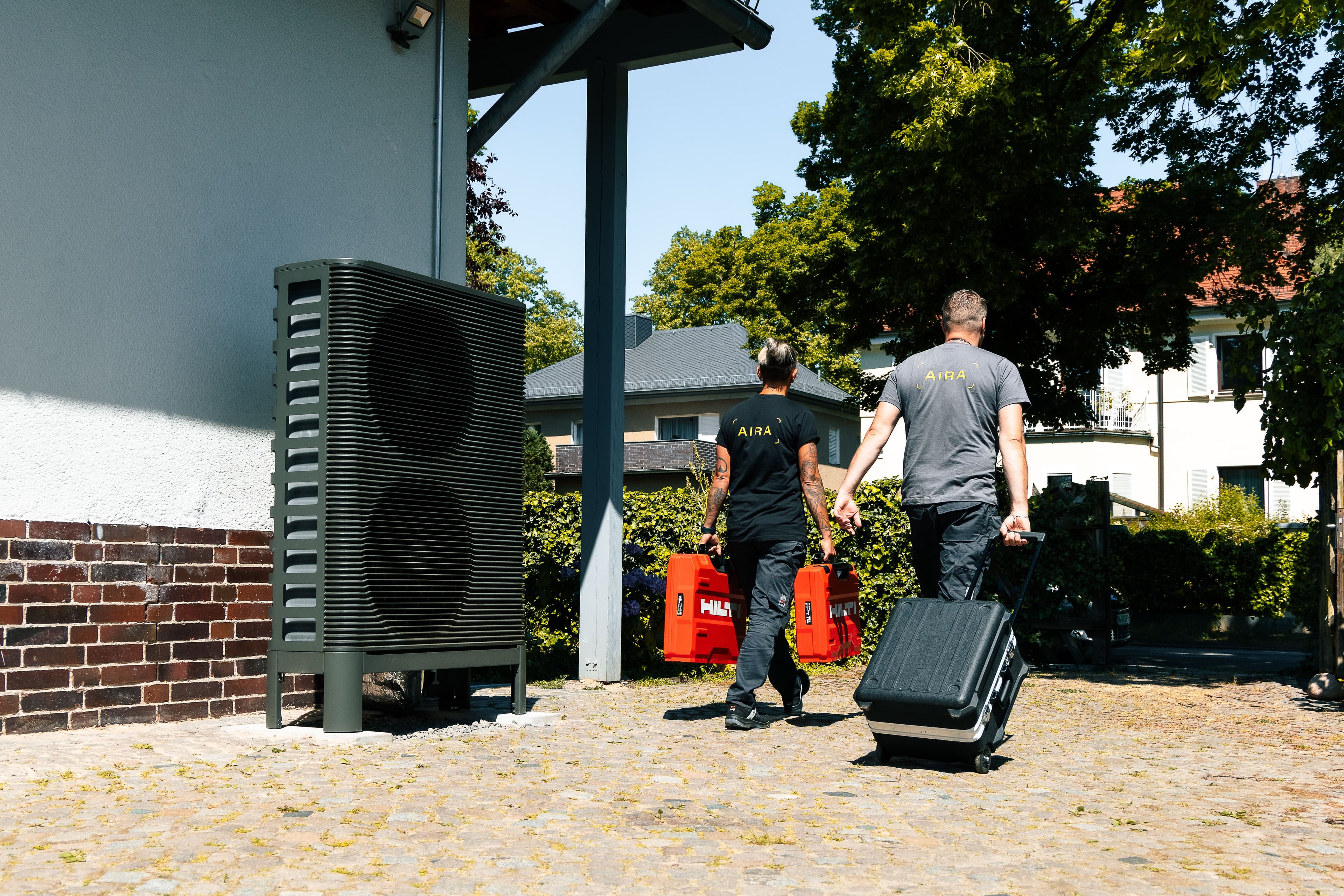 Two Aira Clean Energy Technicians walking past a heat pump following an installation in Berlin