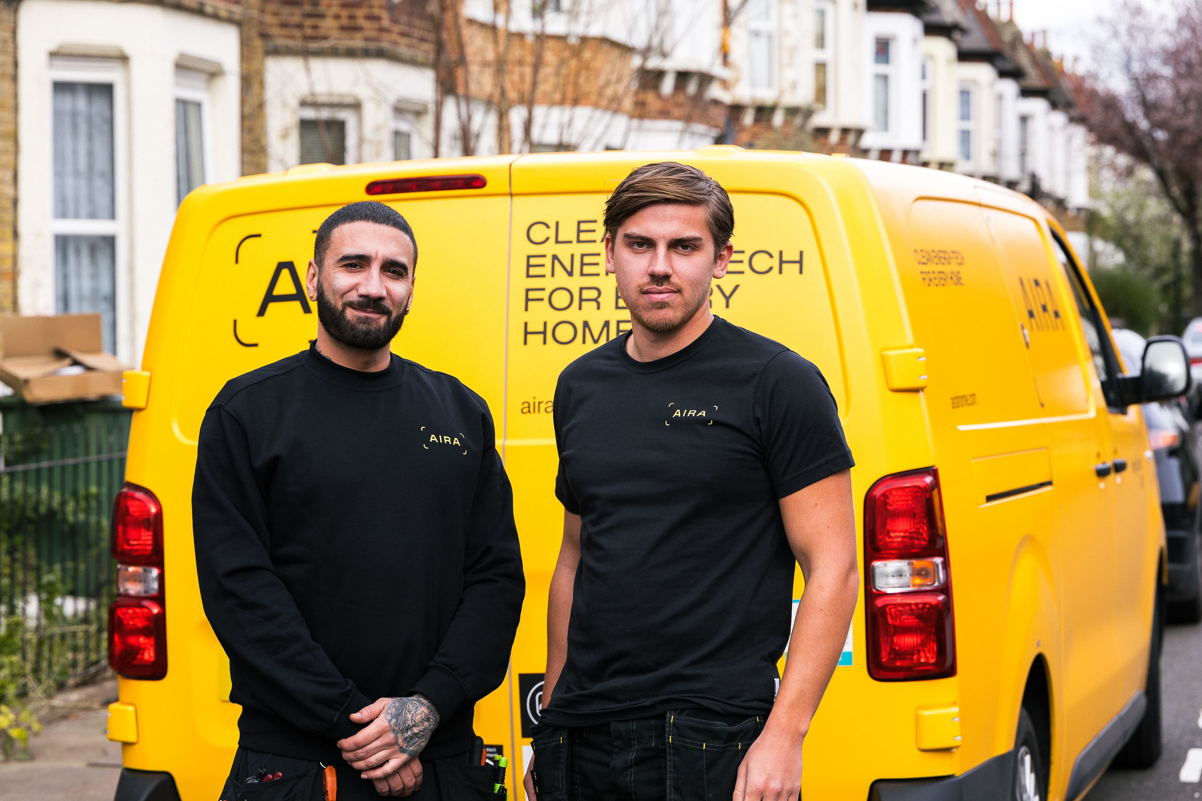 Two Aira heat pump installers standing in front of an Aira van