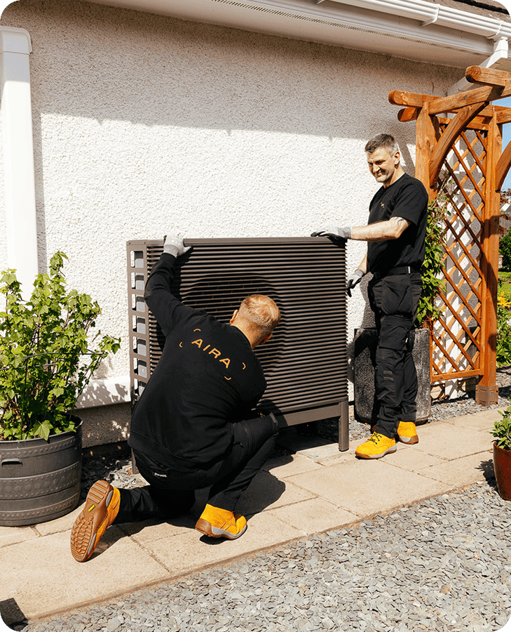 Two Aira Technicians installing the outdoor unit of the Aira Heat Pump outside a home